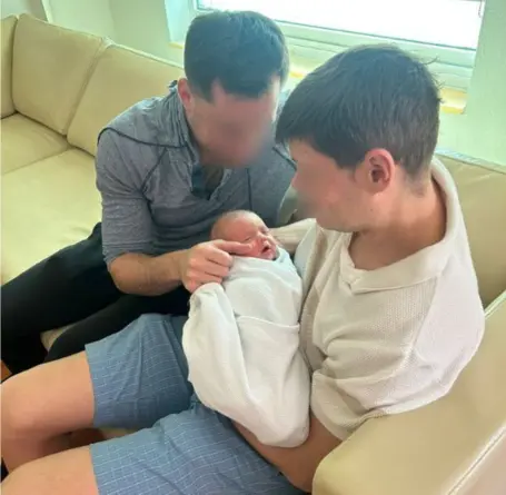 Two gay parents holding their newborn baby for the first time after birth through surrogacy in Mexico